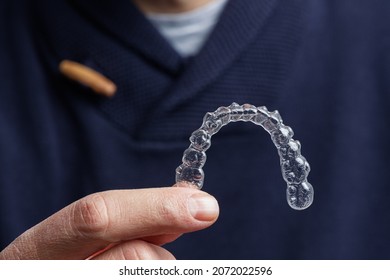 Man Holding One Transparent Aligner. Invisalign Orthodontics Concept