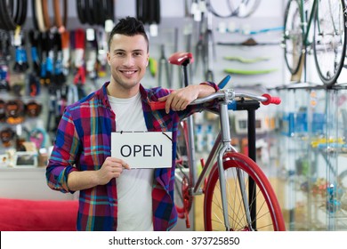 Man Holding Open Sign In Bike Shop
