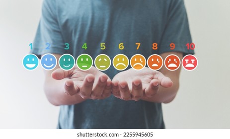 Man Holding of pain measurement scale colorful icon virtual screen interface, emotions from happy blue to red crying, medical technology and futuristic concept.
