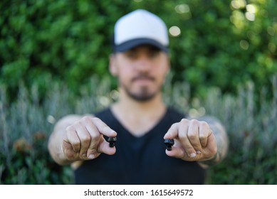 Man holding a pair of wireless earbuds. Selective focus. Close up