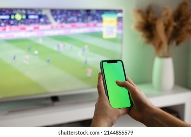 Man Holding Phone In Front Of TV