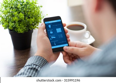 man holding the phone with program smart home on the screen in the office