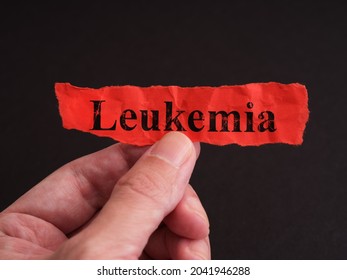 A Man Holding A Piece Of Red Paper With The Word Leukemia On It. Close Up.