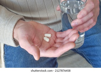 Man Holding Pills And A Glass Of Water.  Healthcare And Medical Concept.