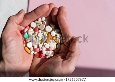 man holding pills on hand.Overdose of medication. A lot of pills spilled on table. Attempt of suicide.Economic crisis and medicine problems. Virus pandemic.Copy space