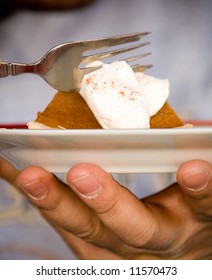 Man Holding A Plate And Eating A Piece Of Pumpkin Pie With Whipped Cream