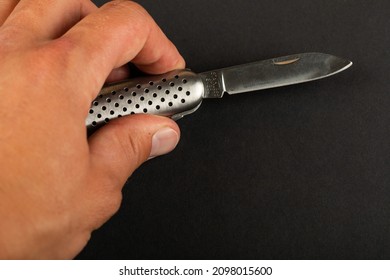 Man Holding Pocket Knife In Hand On Black Background