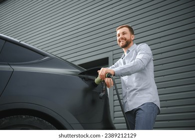 Man Holding Power Charging Cable For Electric Car In Outdoor Car Park. - Powered by Shutterstock