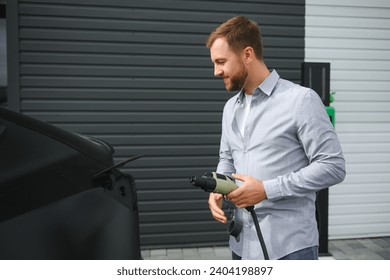 Man Holding Power Charging Cable For Electric Car In Outdoor Car Park. - Powered by Shutterstock