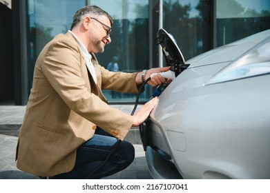 Man holding power connector for electric car.