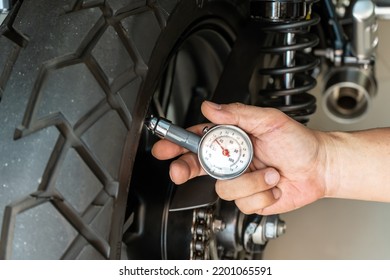 Man holding pressure gauge for checking  motocycle tyre pressure ,maintenance,repair motorcycle concept in garage .selective focus