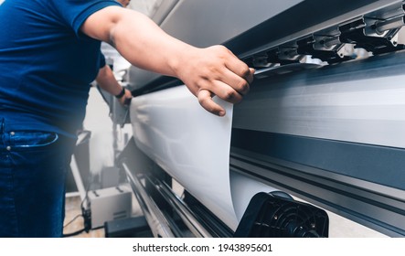 man holding printable material on alarge format printing plotter.graphic design and advertising concept. - Shutterstock ID 1943895601