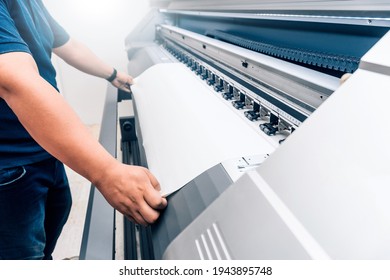 man holding printable material on alarge format printing plotter.graphic design and advertising concept. - Shutterstock ID 1943895748