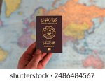 Man holding Qatar passport in hand and world map in background