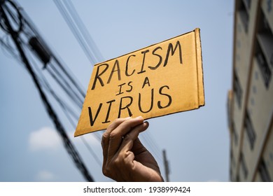 A man holding Racism is a Virus sign