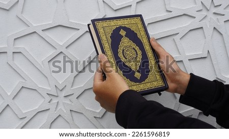 Man Holding and reading quran. Islamic Background. Arabic on the cover translated with Quran. pegang quran. muslim. muslimah