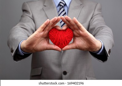 Man holding a red woolen heart concept for valentine's day, business customer care, charity, social and corporate responsibility