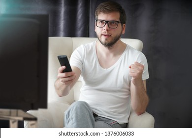 man holding remote control and watching football on TV                   - Shutterstock ID 1376006033