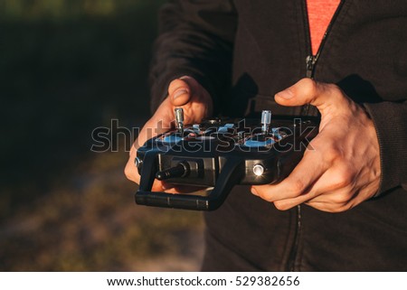 Man holding remote controller in hands close-up. Male hands piloting rc car, drone or helicopter. Pilot running his vehicle with transmitter outdoor, free space