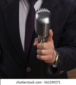 Man Holding A Retro Microphone Over Black Background.