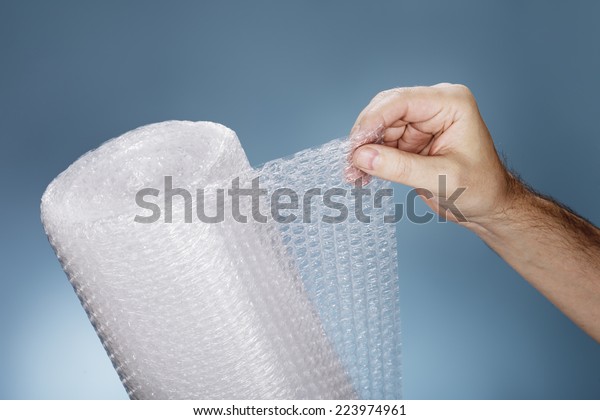 Man holding a roll\
of plastic bubble wrap.