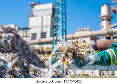 Man Holding Shredded Municipal Waste In Front Of Rotary Cement Kiln Used As Alternative Fuel