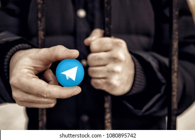 Man Holding Sign Of Blue Coin Depicting White Airplane ICO Gram. Concept Telegram Messenger Is Banned. Roskomnadzor Blocked Telegram Service