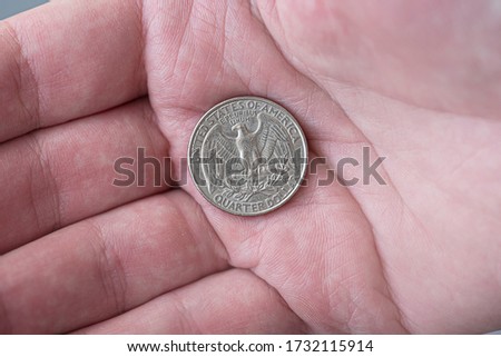 A man holding silver American quarter dollar coin, 25 cents, USA
