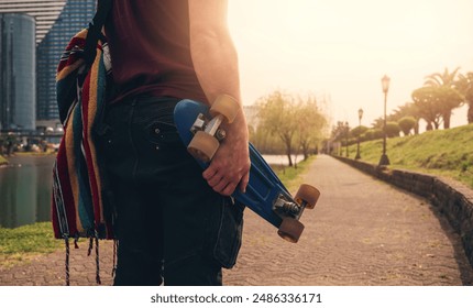 Man holding skateboard in urban setting during sunset - Powered by Shutterstock