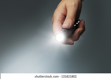 Man holding a small but powerful led flashlight in his hand.