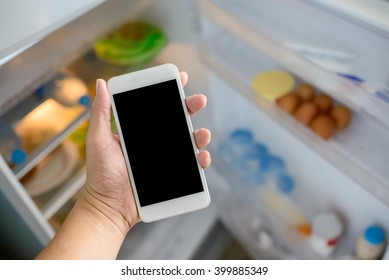 man holding smart phone connected to refrigerator