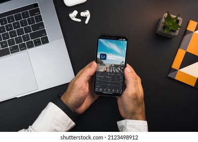 Man holding a smartphone with Adobe Photoshop Lightroom app on the screen on black background table. Office environment. Rio de Janeiro, RJ, Brazil. January 2022.