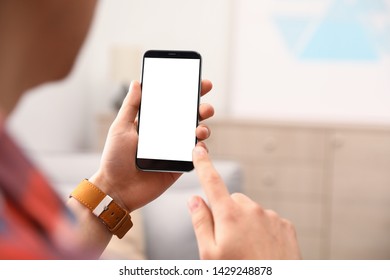 Man holding smartphone with blank screen indoors, closeup of hands. Space for text