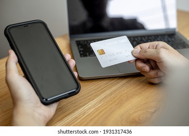 A man holding a smartphone and a credit card, he is doing online shopping through a smartphone app by paying credit card payments. Online shopping ideas with a credit card.
