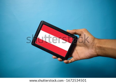 Man holding Smartphone with Flag of Austira. Austria Flag on Mobile Screen isolated On Blue Background
