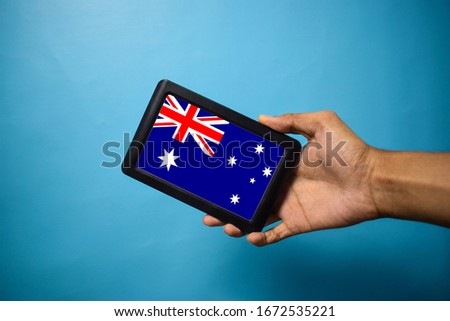 Man holding Smartphone with Flag of Australia. Australia Flag on Mobile Screen isolated On Blue Background