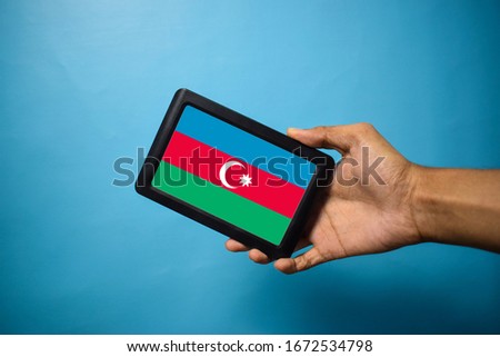 Man holding Smartphone with Flag of Azerbaijan . Azerbaijan Flag on Mobile Screen isolated On Blue Background