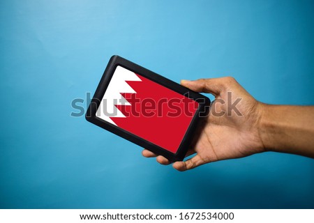 Man holding Smartphone with Flag of Bahrain. Bahrain Flag on Mobile Screen isolated On Blue Background