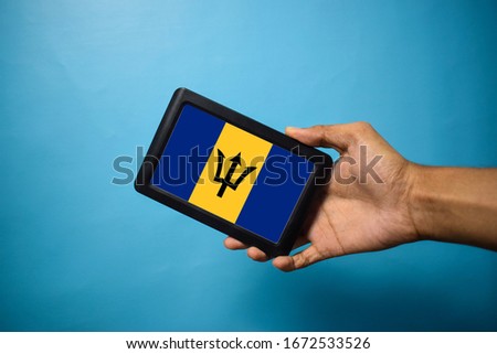 Man holding Smartphone with Flag of Barbados. Barbados Flag on Mobile Screen isolated On Blue Background