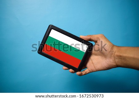 Man holding Smartphone with Flag of Bulgaria. Bulgarian Flag on Mobile Screen isolated On Blue Background