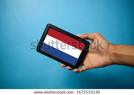 Man holding Smartphone with Flag of Netherlands. Netherland Flag on Mobile Screen isolated On Blue Background