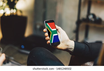 Man Holding Smartphone With Flag Of South Africa. South Africa Flag On Mobile Screen.