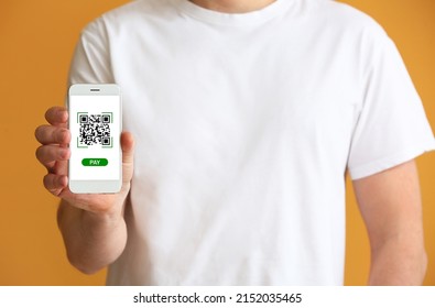 Man holding smartphone with QR code on screen against orange background, closeup