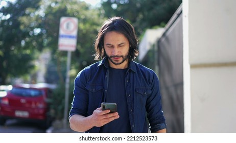 Man Holding Smartphone Walking In Urban City Street. Tracking Motion Shot Of A Person Checking Phone Going Forward