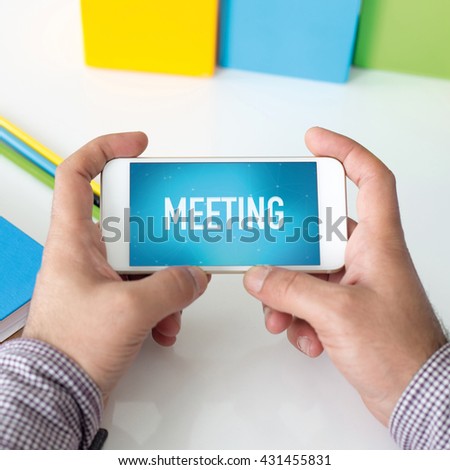 Man holding smartphone which displaying Meeting