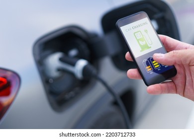 Man holding smartphone while charging car at electric vehicle charging station, closeup. - Powered by Shutterstock