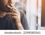 man holding smoking a cigarette in hand. Cigarette smoke spread. dark background