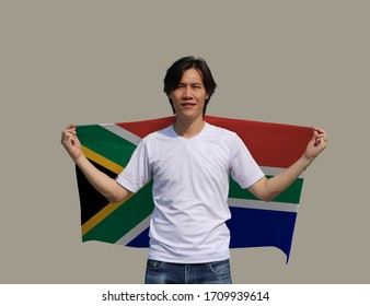 The Man Is Holding South Africa Fabric Flag On His Shoulder On Grey Background.