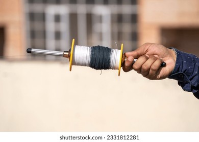 man holding spool charkhi of string with glass covering showing fighting kites flown on sankranti uttarayan independence day in Delhi
