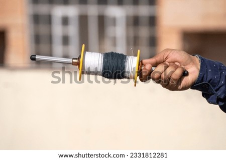 man holding spool charkhi of string with glass covering showing fighting kites flown on sankranti uttarayan independence day in Delhi